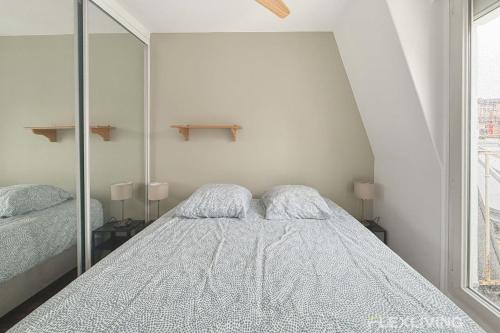 une chambre blanche avec un lit et un miroir dans l'établissement Flexliving - One bedroom - Croix Nivert, à Paris
