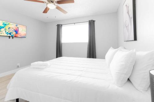 a bedroom with a white bed with a ceiling fan at Charming Two Bedroom Sleeps 6! Close To Strip! in Las Vegas