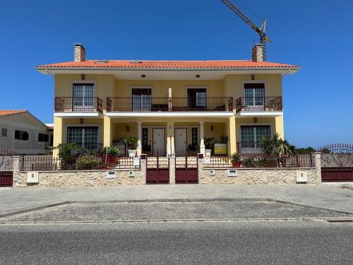 a yellow house with a balcony on a street at Luz Vivenda in Nazaré