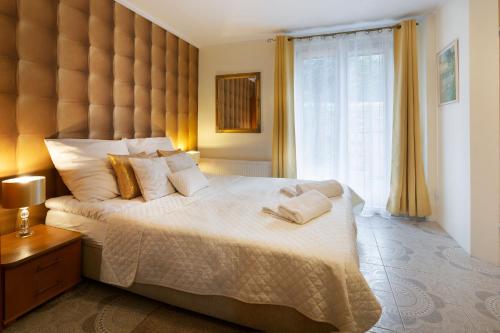 a bedroom with a large bed with two towels on it at APARTAMENTY VILLA PIGMALION - sauna, jacuzzi, parking, ogród in Kudowa-Zdrój