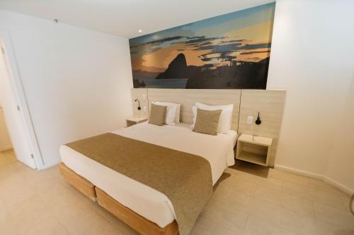 a bedroom with a large bed with a painting on the wall at Hotel Orizzonte Niteroi by Atlantica in Niterói