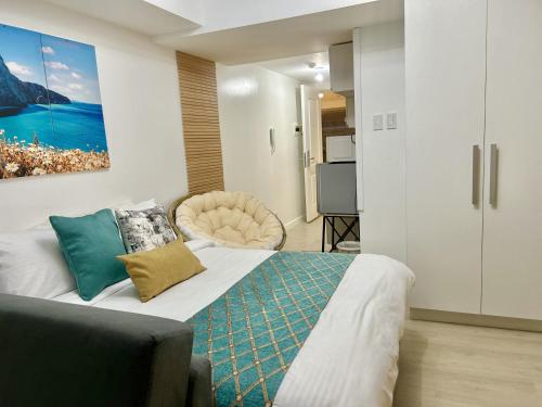 a bedroom with a bed with a couch and a painting on the wall at Studio in Azure North Pampanga in San Fernando