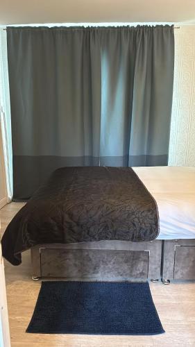 a bed in a room with a curtain and a rug at Guest House in Rose Meare Gardens in Bristol