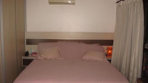 1 dormitorio con 1 cama con sábanas y almohadas rosas en Lindo Duplex Frente Mar, en Cumbuco