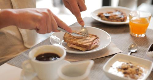 a person eating a sandwich on a plate on a table at Hotel La Bussola in Finale Ligure