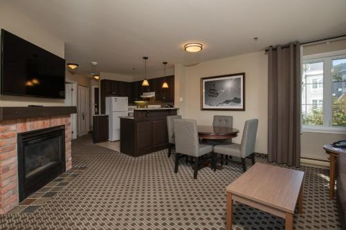 a living room with a fireplace and a kitchen at Holiday Inn Express & Suites Tremblant by IHG in Mont-Tremblant