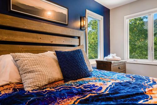 a bedroom with a bed with a wooden headboard and two windows at Mt Views - Sauna - Hot Tub - Adulting - Family Fun in Massanutten