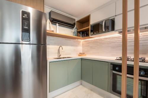a kitchen with a stainless steel refrigerator and cabinets at Flat pé na areia na praia de Porto de Galinhas próximo as piscinas naturais. in Porto De Galinhas