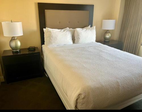 a bed in a hotel room with two lamps on tables at Jockey Resort Suites Center Strip in Las Vegas