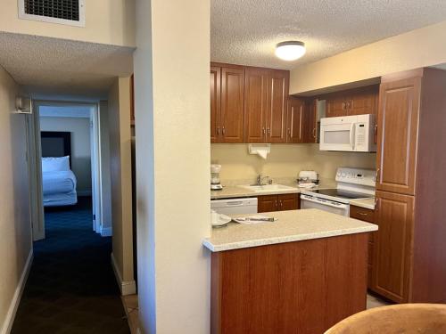 a kitchen with wooden cabinets and a bed in a room at Jockey Resort Suites Center Strip in Las Vegas