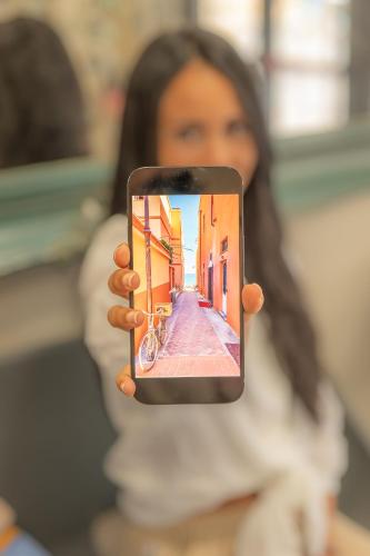 a woman taking a picture of a street with her cell phone at Hotel La Bussola in Finale Ligure