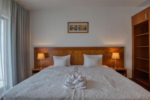a bedroom with a bed with a white flower on it at Tisza Balneum Hotel in Tiszafüred