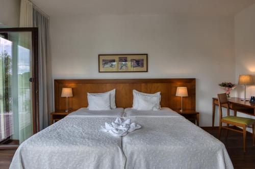 a bedroom with a large bed with a flower on it at Tisza Balneum Hotel in Tiszafüred