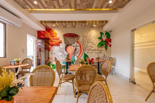 a restaurant with tables and chairs and a wall with flowers at Hotel Stay Here Suites in Santo Domingo