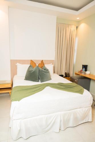 a large white bed with three pillows on it at Hotel Stay Here Suites in Santo Domingo