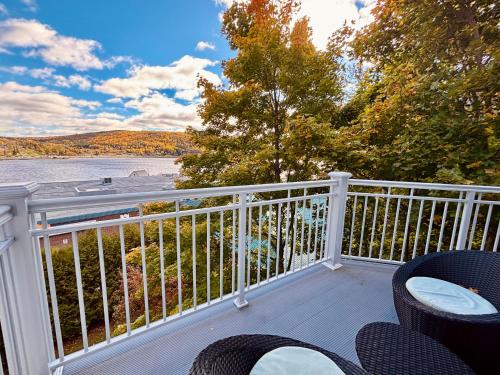 a balcony with chairs and a view of the water at Auberge Sous les Arbres in Gaspé