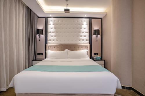 a bedroom with a large white bed with a headboard at Pazhou XANA Deluxe International Hotel Pazhou Convention and Exhibition Center Changgang Metro Station Branch - Free Shuttle Bus to Canton Fair Complex During Canton Fair Period & Free Deliver Service to Guangzhou Baiyun International Airport in Guangzhou
