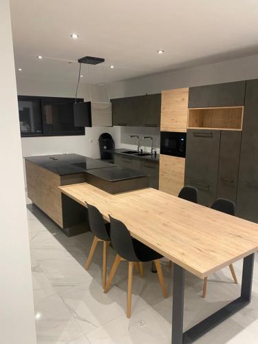 une grande cuisine avec une table et des chaises en bois dans l'établissement Maison neuve proximité des plages, à Plouzané