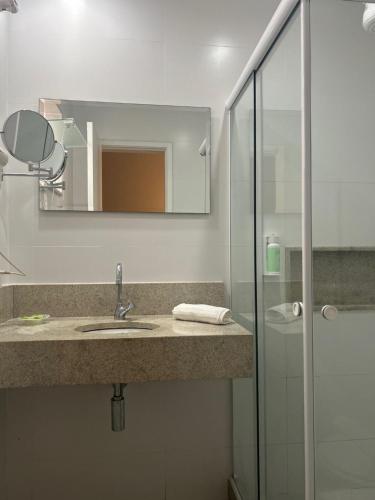 a bathroom with a sink and a glass shower at Hotel Petit Village Icaraí in Niterói