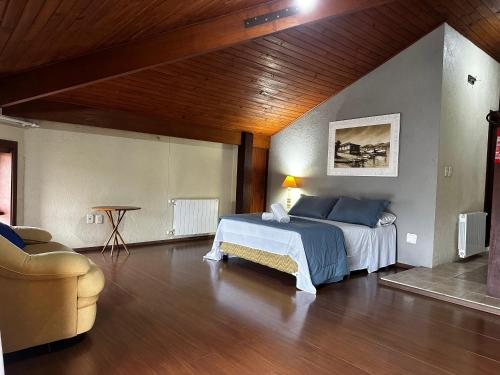 a large bedroom with a bed and a chair at Pousada Canela Garden in Canela