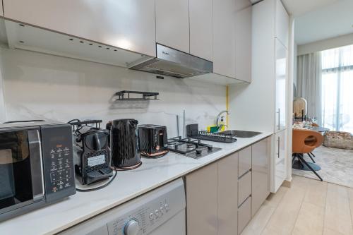 a kitchen with white cabinets and a counter top at Nasma Luxury Stays - Azizi Riviera 6 Cozy Studio with Burj Khalifa View in Dubai