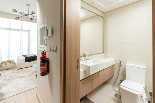 a bathroom with a sink and a toilet and a mirror at Nasma Luxury Stays - Azizi Riviera 6 Cozy Studio with Burj Khalifa View in Dubai