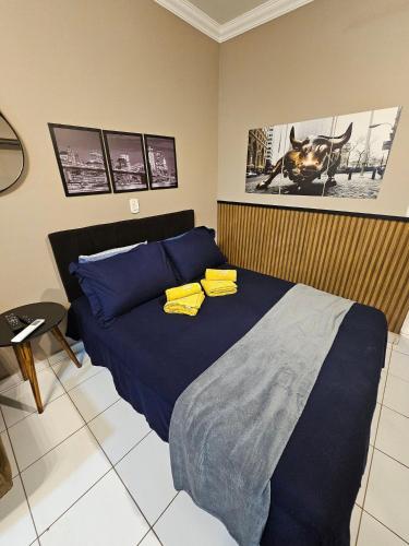 a bedroom with a bed with blue sheets and yellow pillows at Edifício Belluno in Ribeirão Preto