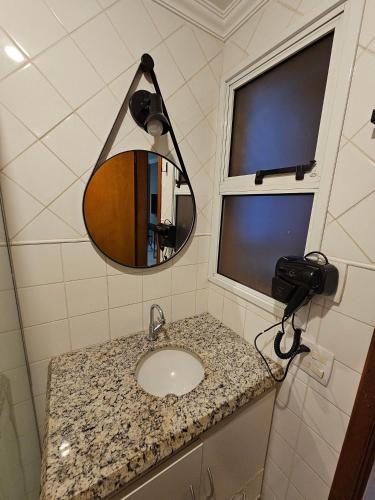 a bathroom with a sink and a mirror at Edifício Belluno in Ribeirão Preto