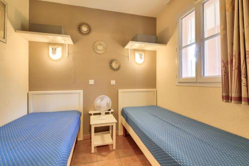 une chambre avec deux lits et une fenêtre dans l'établissement Résidence le Hameau des Issambres - maeva Home - Appartement 2 pièces 4 personnes - Sélection MAE-4601, aux Issambres