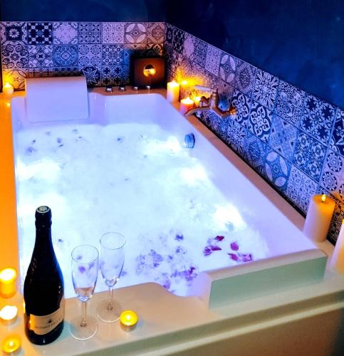 - une baignoire avec deux verres et une bouteille de vin dans l'établissement L'Evasion Scandinave, SPA XXL, Écran cinéma, Lit king size, day use, 10 min centre, à Amiens