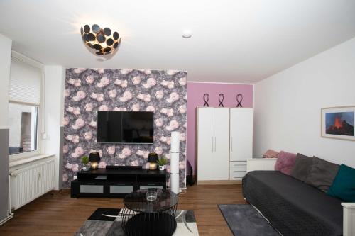 a living room with a black couch and a pink wall at GME Easy FlexHome Berlin Spandau in Berlin