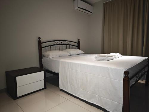a bedroom with a bed with white sheets and a night stand at Pacific FairPrice in Nadi