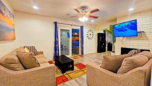 a living room with two couches and a flat screen tv at Tropical Paradise in Fresno