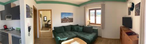a living room with a green couch in a room at Zur neuen Post Landgasthof in Herzogsreut