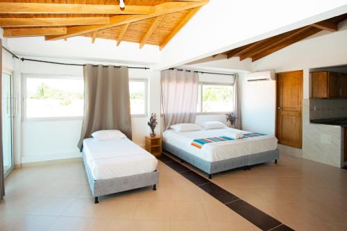 two beds in a room with two windows at Hotel Caribe Coveñas in Coveñas