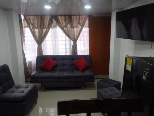 a living room with a blue couch and red pillows at Apartamento hermoso en Ipiales frontera con ecuador in Ipiales