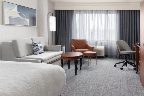 a hotel room with a bed and chairs and a table at Courtyard by Marriott Ontario Rancho Cucamonga in Rancho Cucamonga