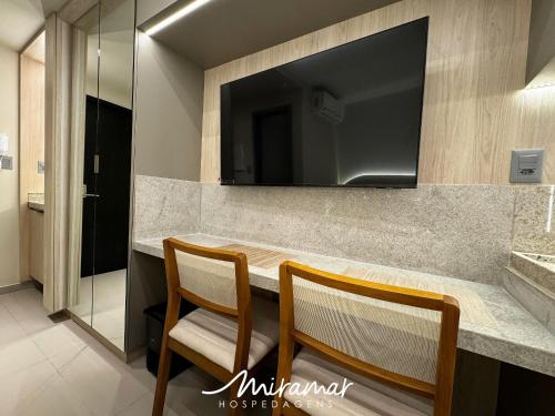 a bathroom with a counter with two chairs and a television at Beach Haus in Tambaú