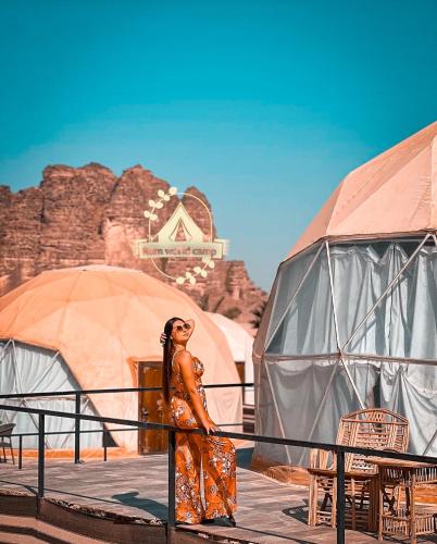 a woman standing next to a fence in front of tents at RUM WORLD BUBBLE lUXURY CAMP in Wadi Rum