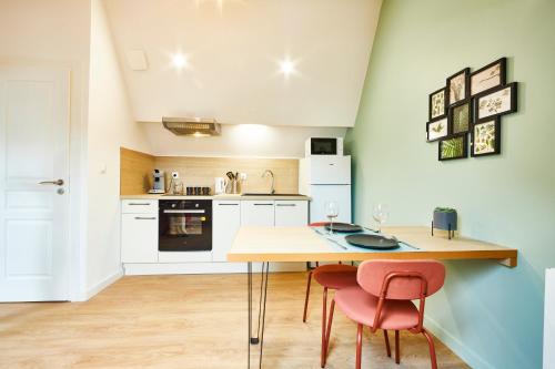 une cuisine avec une table en bois et deux chaises roses dans l'établissement RB-3 Charmant appartement 2 pers dans les combles 3ème étage, à Mulhouse