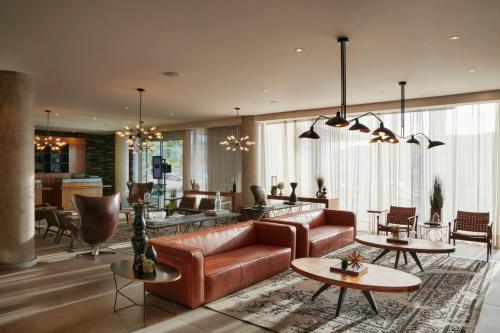 a living room with a leather couch and tables at Four Points by Sheraton Distrito Uno Chihuahua in Chihuahua