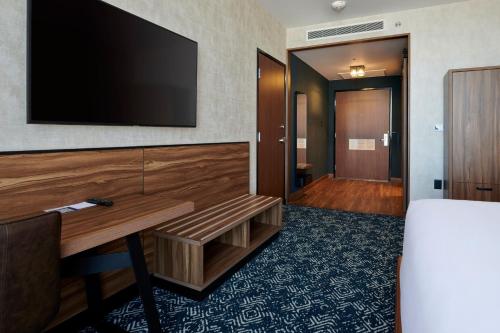 a hotel room with a desk and a flat screen tv at Four Points by Sheraton Distrito Uno Chihuahua in Chihuahua