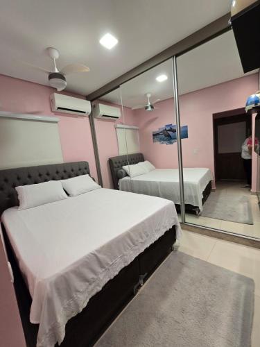 a bedroom with two beds and a mirror at Casa Rosa in Cuiabá