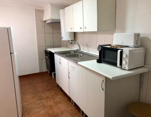 a small kitchen with a microwave and a sink at Casa das Casas Novas - Beco das Avós in Elvas