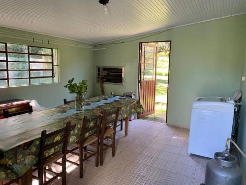 a dining room with a long table and a refrigerator at Colonia Nona Angélica in Farroupilha
