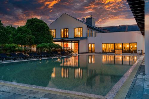 a house with a swimming pool in front of a building at Tisza Balneum Hotel in Tiszafüred