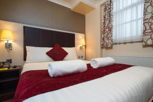 a bedroom with a large bed with two pillows on it at Best Western Buckingham Palace Rd in London