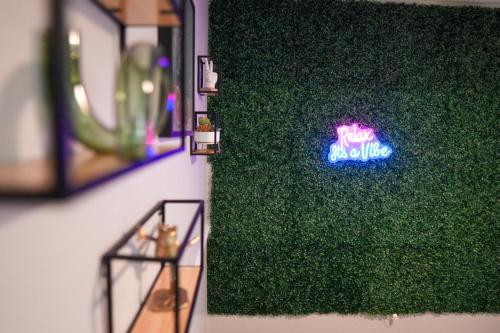 a green wall with a neon sign on it at Luxury & Convenience in South End Charlotte in Charlotte