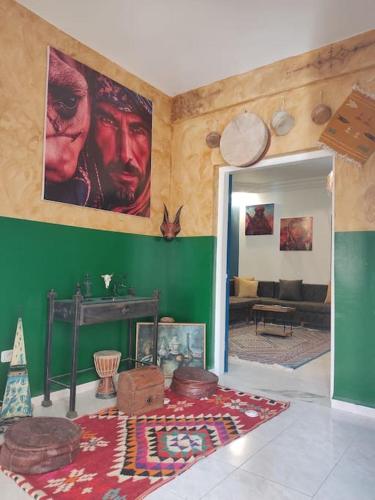 a living room with a green wall with posters on it at Dar Margoum in Tozeur