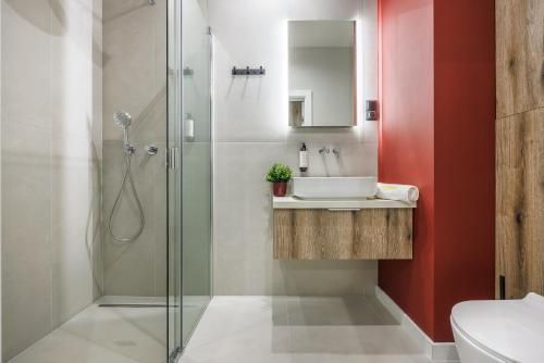 a bathroom with a glass shower and a sink at Emihouse Riverside Apartments in Rzeszów